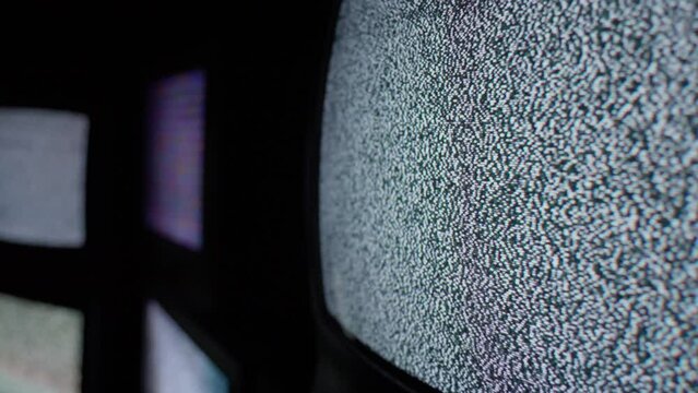 A close up angle of cathode tv screens showing only a steady white noise signal in a dark and isolated room.