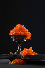 Red caviar in a bowl on a black background. Salmon roe. A delicacy. Delicious food. The texture of...