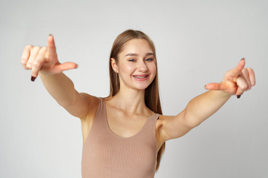 Young Woman Pointing Towards Camera With a Playful Expression in a Studio