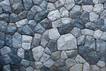 Full frame of natural stone wall cladding showcasing various shade of gray and a textured surface exterior