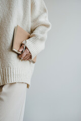 Young woman in beige clothes hold notebook over white wall. Aesthetic neutral pastel colors - 780306395