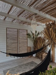 Aesthetic modern boho style home interior design with hammock. Decorations made of straw, rattan, dried palms. Bohemian, coastal, organic modern and tropical interior - 780306751