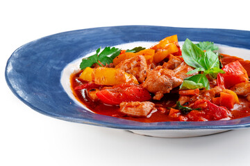 Roast chicken stew with vegetables and tomatoes served in a plate on a white background. Chakhokhbili made from chicken pieces, Georgian cuisine, close up