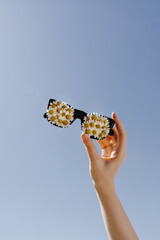 Summer sunny day concept. Sunglasses with chamomile daisy flowers over bright clear blue sky - 780307399