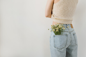 Young pretty woman with chamomile flowers bouquet in jeans pocket. Backside view - 780307543