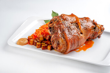 Pork knuckle baked in the oven in a plate with stewed cabbage and potatoes on a white background. Bavarian meat dish