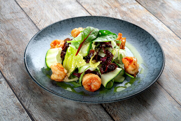 Salad with grilled shrimp and fresh green vegetables, spinach leaves and zucchini. Healthy seafood salad with pesto sauce.