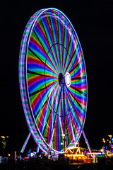 Carnival lights at night - The fun of summertime carnival and fair rides at night with colorful lights on thrill rides and attractions