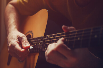 Man playing acoustic guitar at home, low key image - 780311560