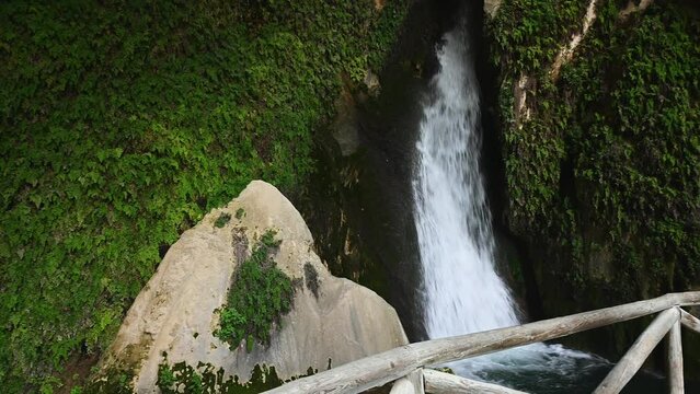 View from a wooden suspension bridge to a waterfall in a cave overgrown with wild ivy, in the mountains of Sierra de Cazorla in the province of Jen in Spain. Beauty in nature