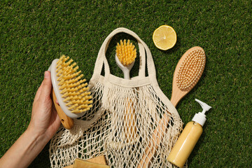 Eco bag, brushes, hand, soap and lemon on green background, top view