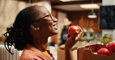 African american buyer enjoying fresh aroma of tomatoes at store, smelling freshly harvested...