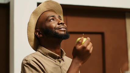 African american man smelling locally grown apples at supermarket, supporting nonpolluting small business by buying bio food. Client choosing fruits from crates, enjoying natural aroma. Camera 1.