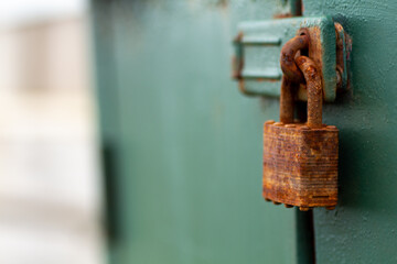 Rusted padlock on green box, corroded by weather and sea air.