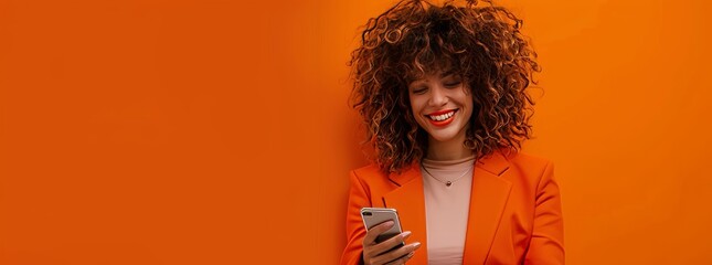 Portrait of smiling african american woman using smartphone isolated on orange background, wearing red sweater with copy space for your text message or promotion banner.