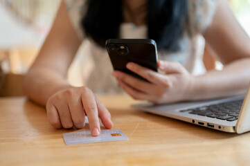 A close-up image of an Asian woman pointing her finger at a credit card on the table.
