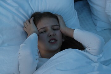 Fototapeta na wymiar Little girl suffering from headache in bed at night