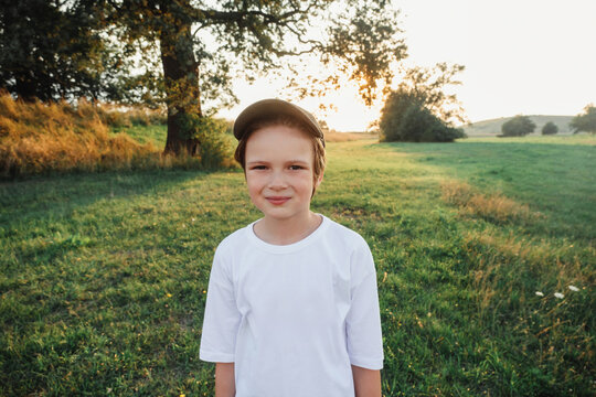 Happy boy smiling on grass field wearing white t-shirt