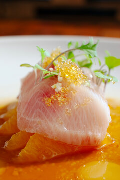 Close up view of piece of fish plated with citrus and roe