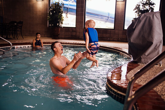 Toddler jumping into dad's arms while playing indoors in pool