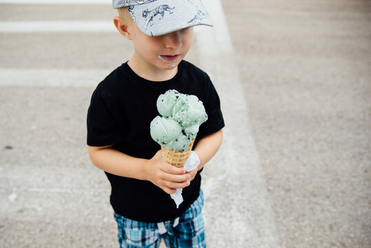 Detail view of small boy holding large ice cream cone outside