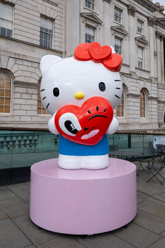 Hello Kitty statue with red heart-shaped balloon in front of a building in London, UK