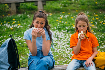 Beautiful children eating a sandwich and a banana in the park.