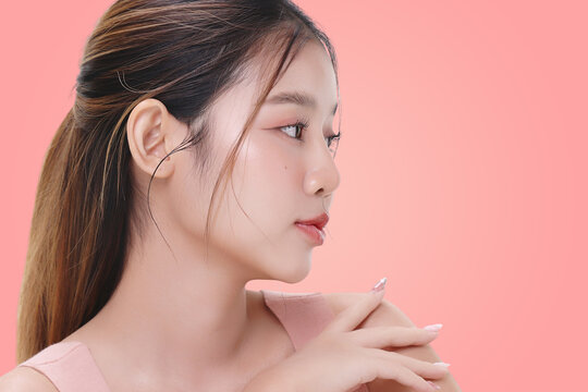 Close-up portrait of young Asian beautiful woman with K-beauty make up style and healthy and perfect skin isolated on pink background for skincare commercial product advertising.