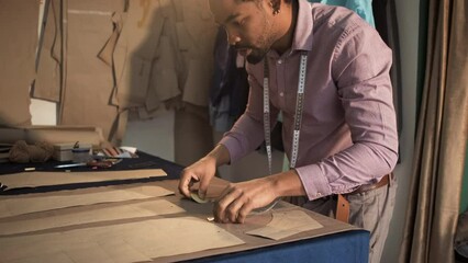 Male fashion tailor working on the measurements for the suit design in his workshop.