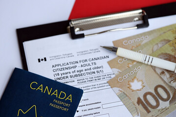 Application for Canadian citizenship for adults on table with pen, passport and dollar bills close up