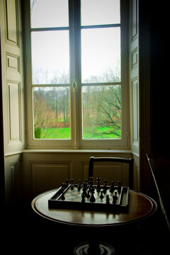 A strategic chessboard setup is ready for a game in a well-lit room with a scenic window view
