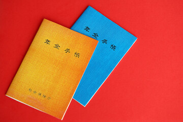 Japanese pension insurance booklets on table. Blue and orange pension book for japan pensioners close up