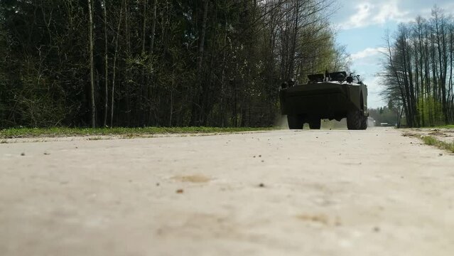 A green, mid-20th century Soviet armored reconnaissance and patrol vehicle in motion, kicking up dust, designed for military reconnaissance.