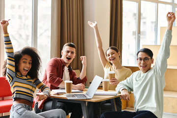 A group of students from different backgrounds collaborate at a table with laptops for a project or study session.