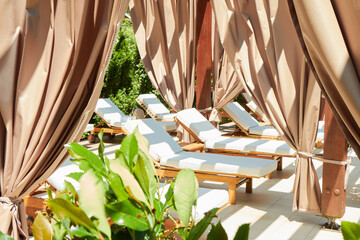 A serene setting at a luxury resort featuring a row of elegant cabanas with flowing drapes and...