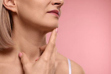 Fototapeta na wymiar Woman touching her neck on pink background, closeup