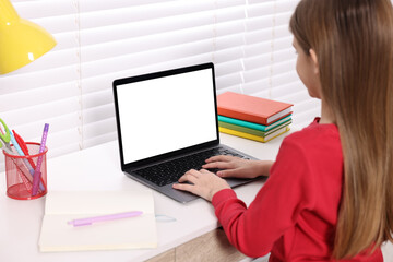 E-learning. Girl using laptop during online lesson at table indoors