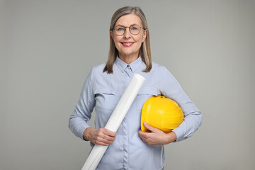 Architect with hard hat and draft on grey background