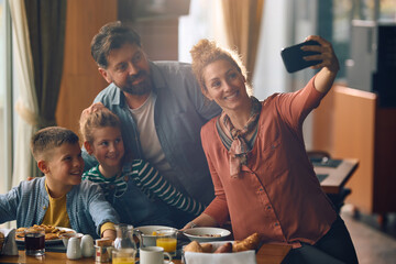 Happy family taking selfie during their breakfast in  hotel restaurant.