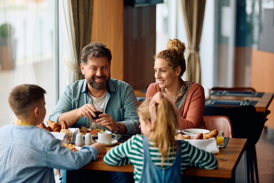 Happy family talking while having breakfast in  restaurant at hotel.