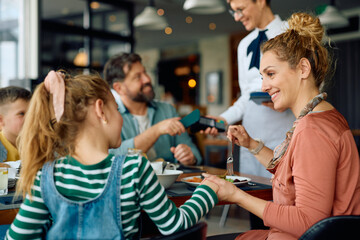 Happy mother and daughter communicating during family breakfast in  restaurant.