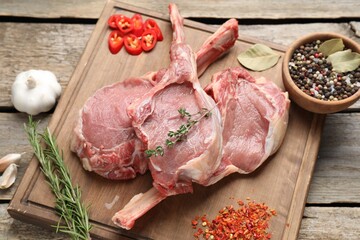 Fresh tomahawk beef cuts and spices on wooden table, above view
