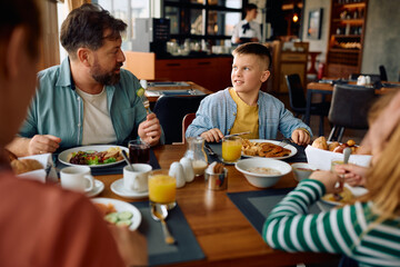 Father and son talking during family breakfast in hotel restaurant.