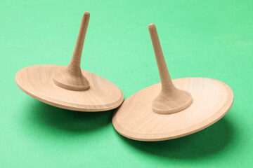Two wooden spinning tops on aquamarine background, closeup