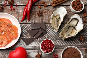 Natural aphrodisiac. Different food products and heart model on wooden table, flat lay