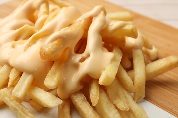 Delicious french fries with cheese sauce on board, closeup
