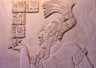 Bas relief carving of mayan god smoking with maya hieroglyphics, Palenque, Mexico.
