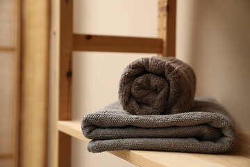 Soft towels on wooden shelf indoors, closeup