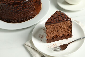 Piece of delicious chocolate truffle cake on white marble table