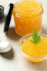 Fresh pike caviar in bowl, parsley and spoon on light grey table, closeup